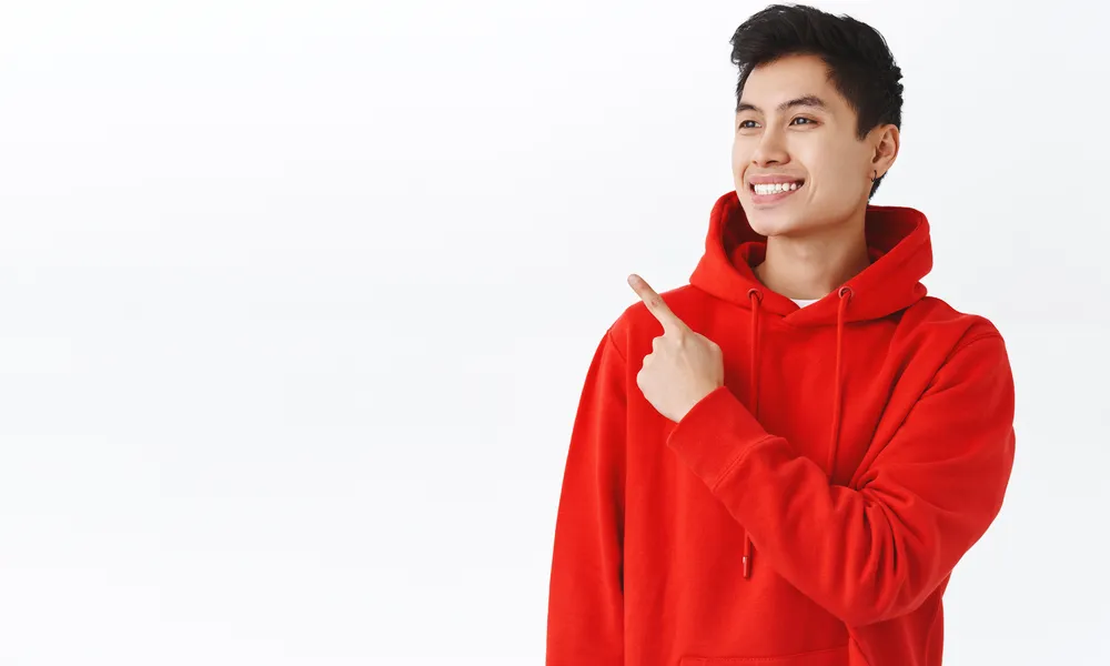 waist-up-portrait-attractive-happy-hipster-man-red-hoodie-earring-smiling-pleased-pointing-looking-upper-left-corner-with-delighted